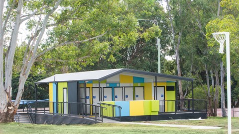 Brightly Coloured Toilet Block Building on Grass with Netball Court in Foreground
