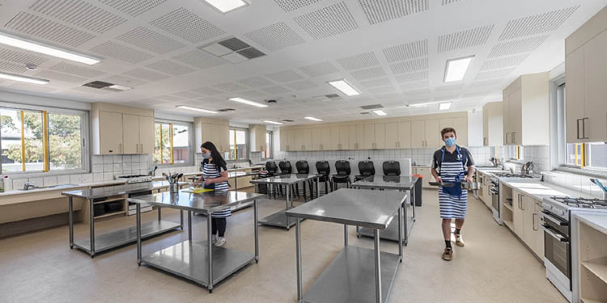 Interior Home Economics Classroom with Steel Benches, Cookware and Two Students in Aprons