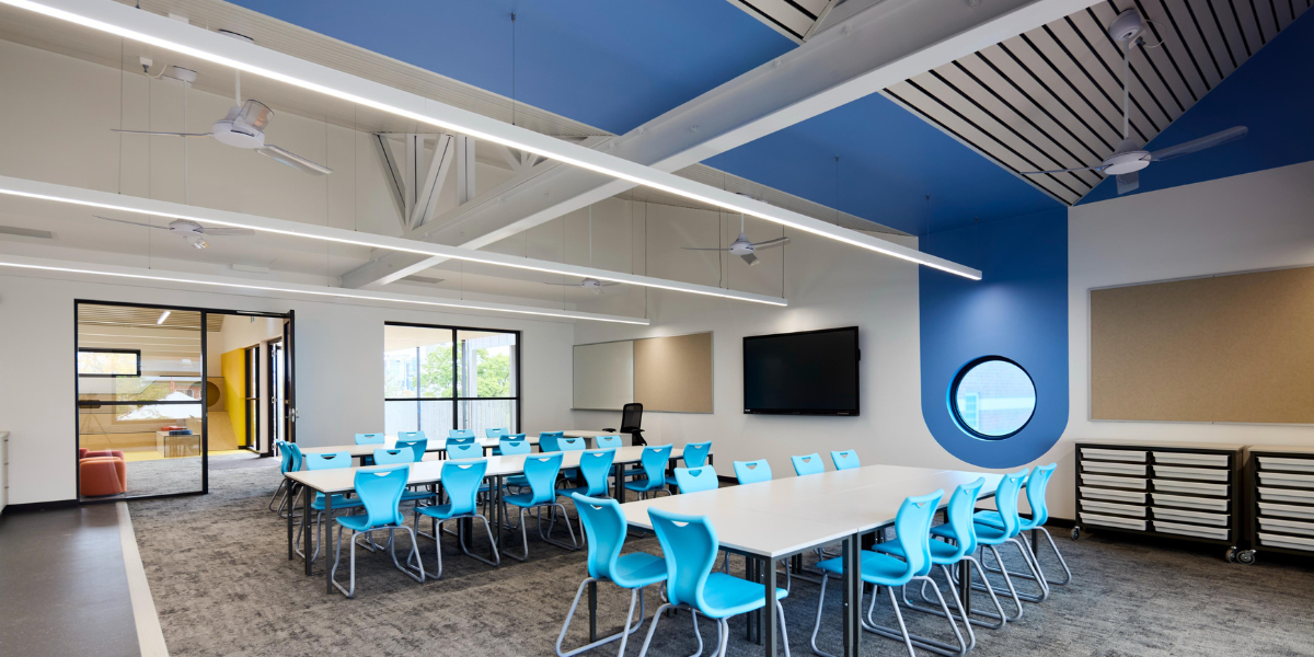 Modern classroom at Highgate Primary School featuring blue ceiling panels, colourful student seating, large windows and natural light.