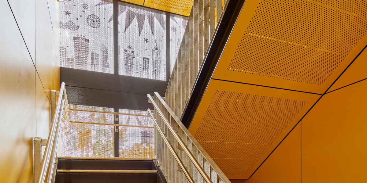 Interior staircase at Highgate Primary School featuring warm timber-look finishes, yellow architectural details and natural light.