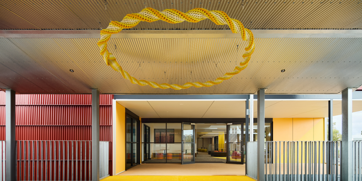 Interior view of Highgate Primary School's modular learning facility, featuring a yellow circular ceiling feature, colourful finishes and glass-partitioned learning spaces.