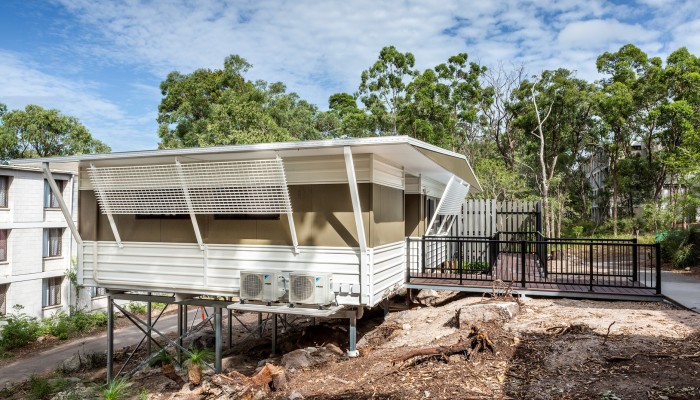 Modular Construction Building on a small hill with railed entry and privacy screens on the windows 