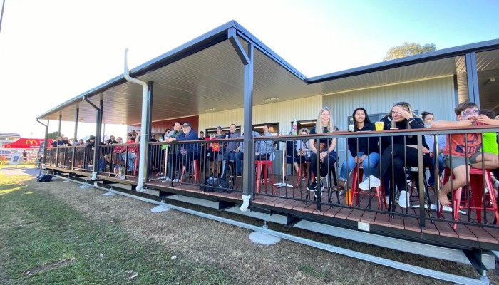 Exterior Sports Building with People Sitting on Deck Facing Sports Field