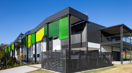 Modular Building with Green Facade, Grey Awnings and Fencing