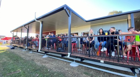 Exterior Sports Building with People Sitting on Deck Facing Sports Field