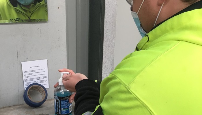 Man in High Vis and Mask Sanitising Hands