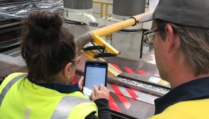 Woman and Man in High Vis looking at a Tablet with Factory Interior in Background