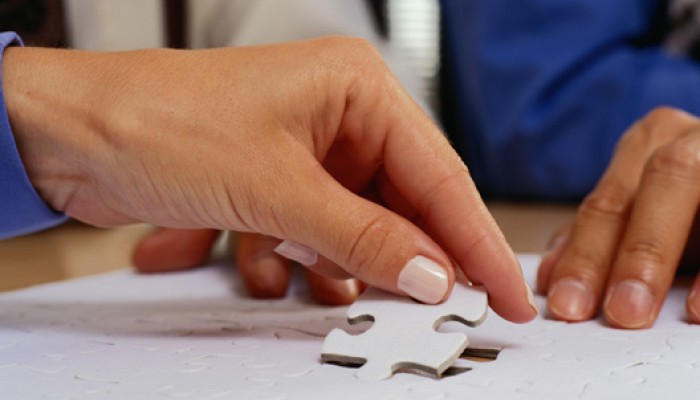 A Hand placing a puzzle piece in a finished puzzle