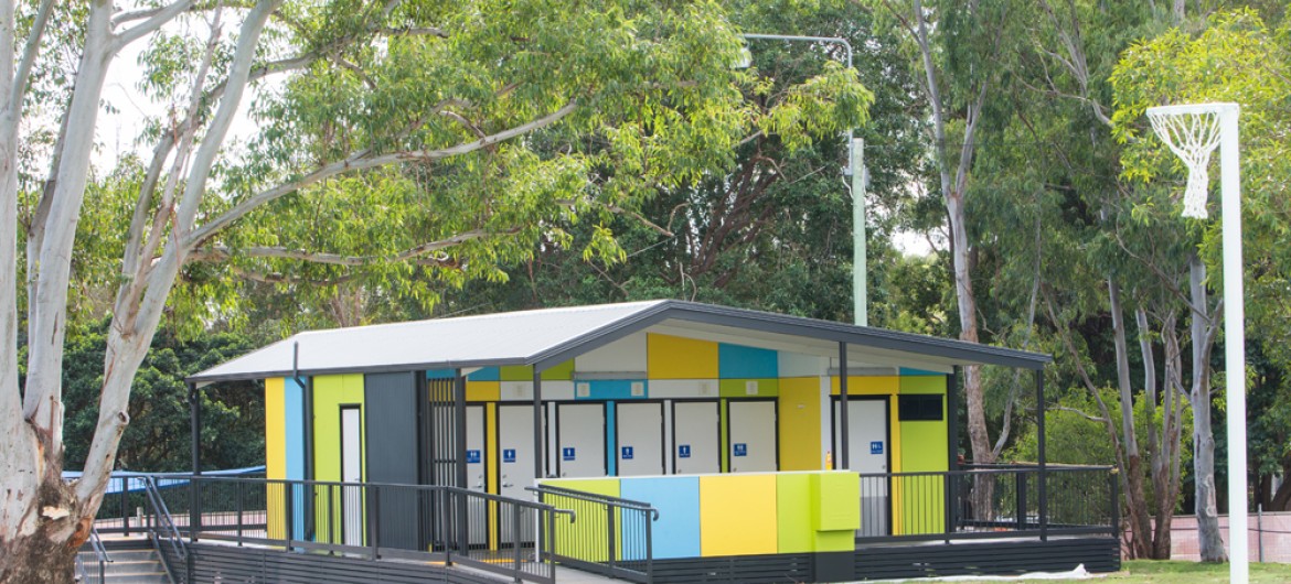 Brightly Coloured Modular Toilet Block on Lawn Beneath Trees