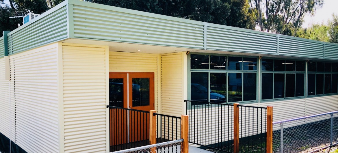 Fenced Modular School Building with Corrugated Metal Cladding, Windows and Double Door