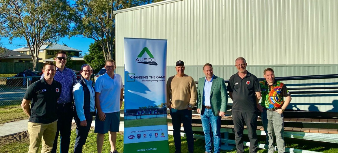 Eight Men Standing with Ausco Modular Sign Outside