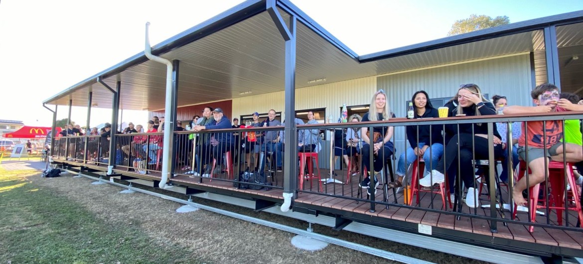 Exterior Sports Building with People Sitting on Deck Facing Sports Field