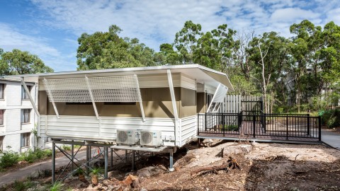 Modular Construction Building on a small hill with railed entry and privacy screens on the windows 