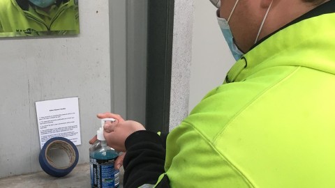 Man in High Vis and Mask Sanitising Hands