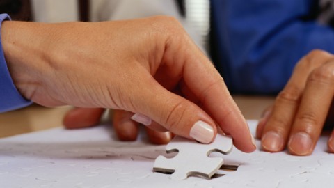 A Hand placing a puzzle piece in a finished puzzle